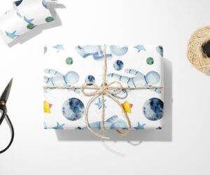 Astronaut & Moon Wrapping Paper with stars and a pair of scissors, inspired by the moon.