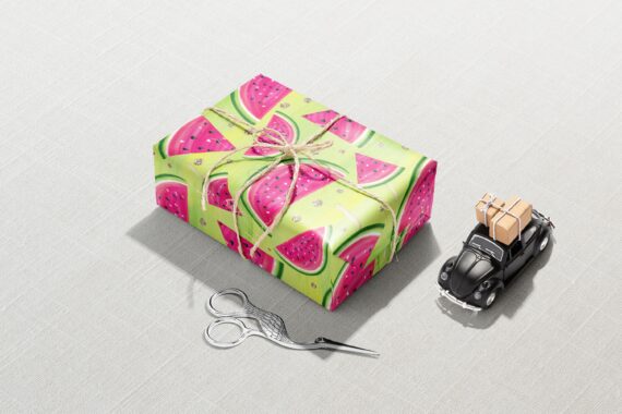 A Watermelon Fruit Wrapping Paper wrapped gift with scissors next to it, perfect for a Birthday or Baby Shower gift.