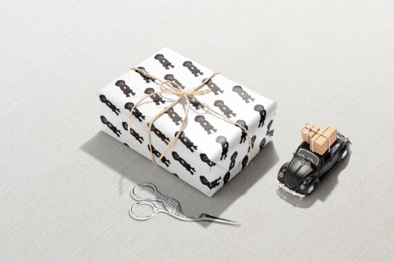 A gift box with a pair of scissors wrapped in Black Labradoodle Wrapping Paper.
