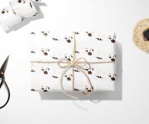 Sentence with product name: Jack Russell Pitbull wrapping paper and scissors on a white surface.