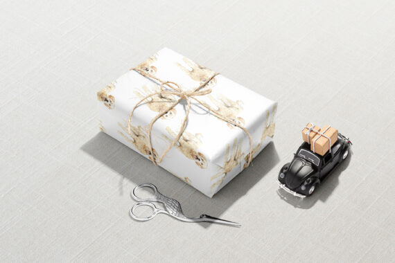 A Christmas gift wrapped in Goldendoodle Dog Wrapping Paper next to a toy car and scissors.