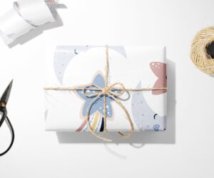 Gift wrapped in Moon and Stars Wrapping Paper with scissors on a white surface.