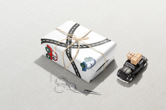 A gift box with scissors and a toy car ready to hit the Cars and Roads Wrapping Paper.