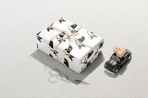 A gift box with scissors and a pair of Boxwood Corgi Dog wrapping paper, wrapped in wrapping paper.