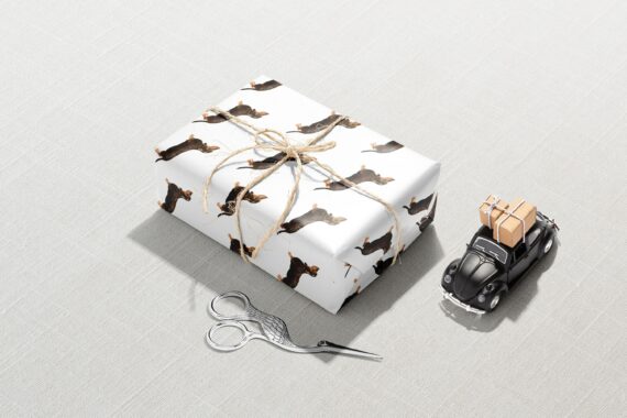 A Christmas gift wrapped in Black Dachshund Wrapping Paper with scissors.