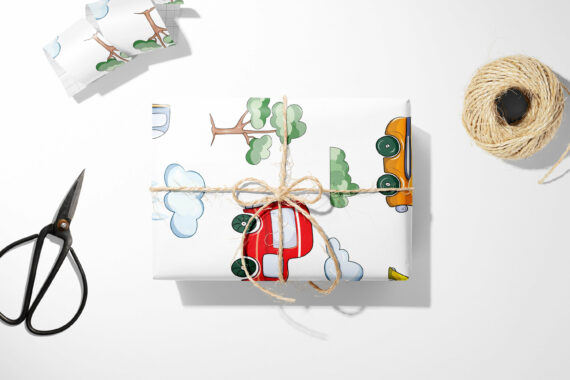 A Christmas gift wrap with scissors and Cars, Clouds, & Trees Wrapping Paper next to it.